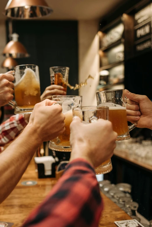 four friends having drinks at the bar and sharing glasses with each other