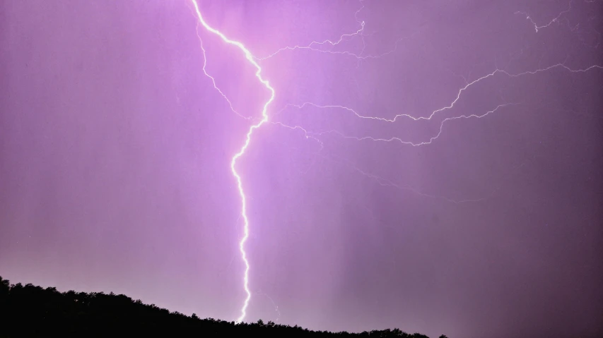 a group of lightning lights up the sky behind two horses