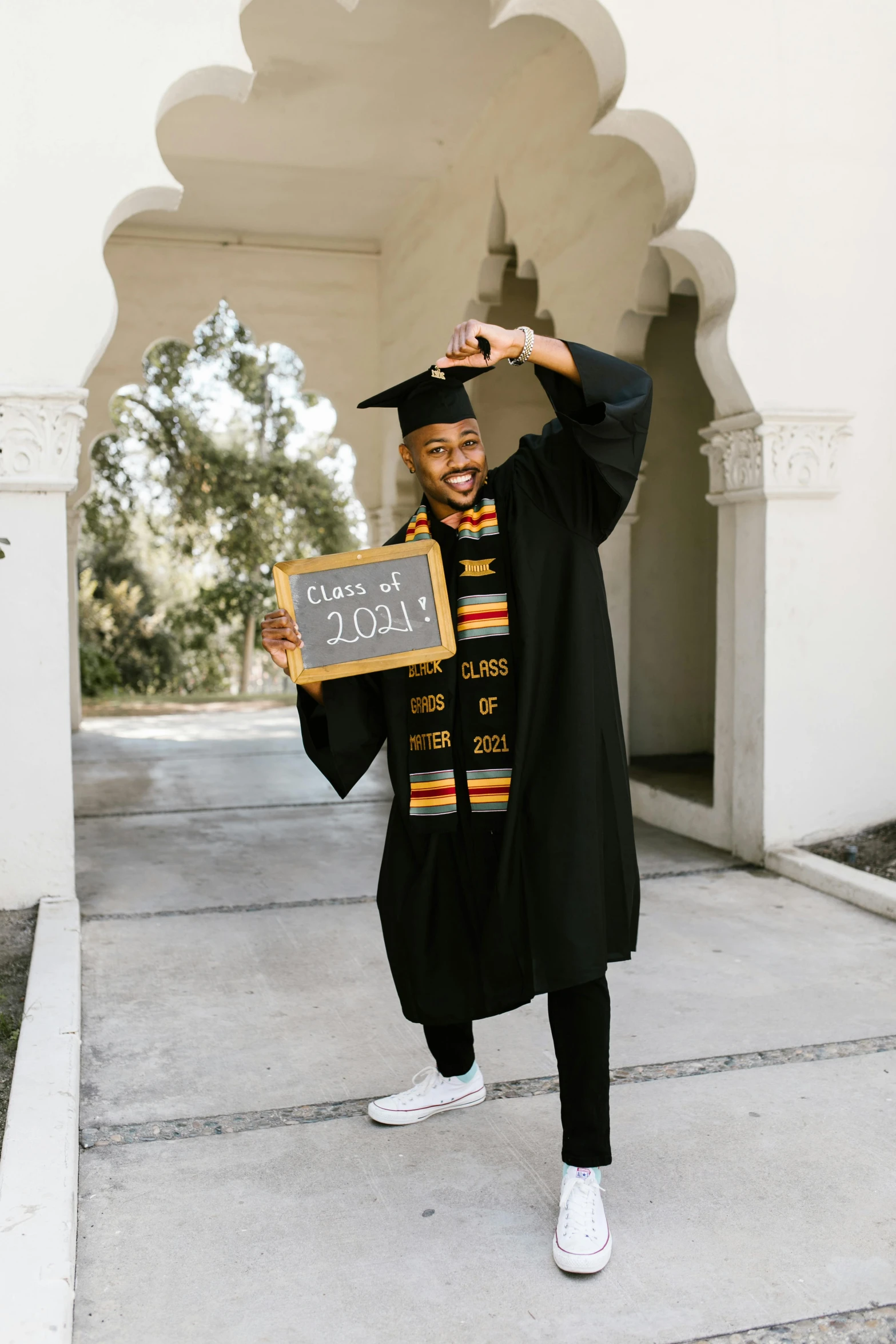 a black male graduates smiling and holding a sign
