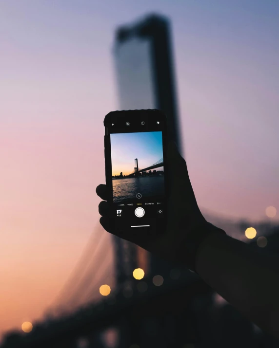 someone holding up a smart phone in front of the skyline of a city