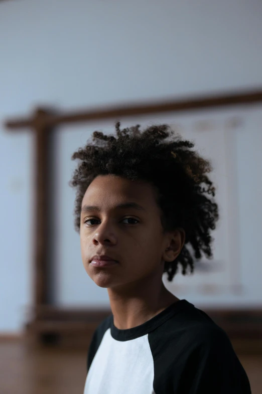 a boy with curly hair standing in a room