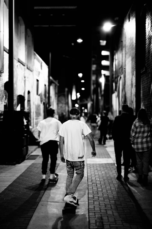 two men walk down an alley way with skateboards