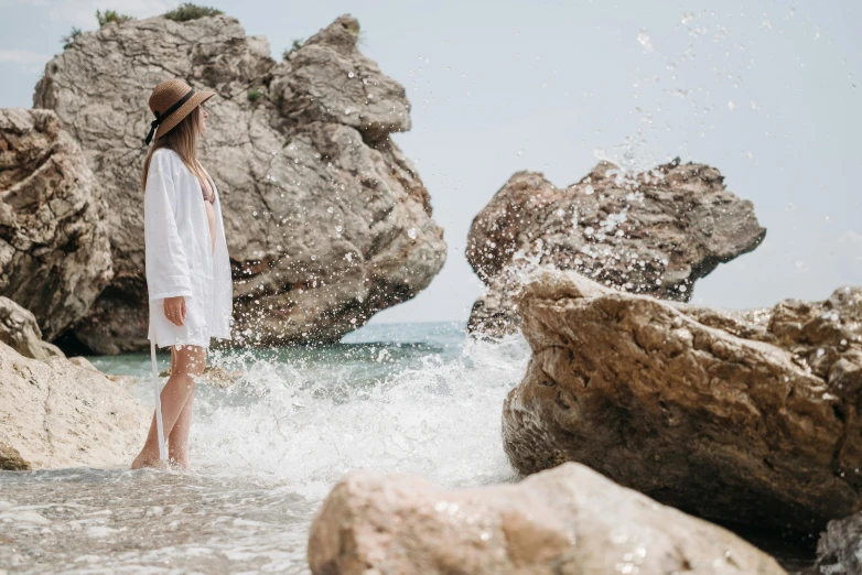 a young woman wearing a white dress standing in a body of water