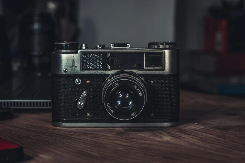 an old camera and a laptop on a wooden table