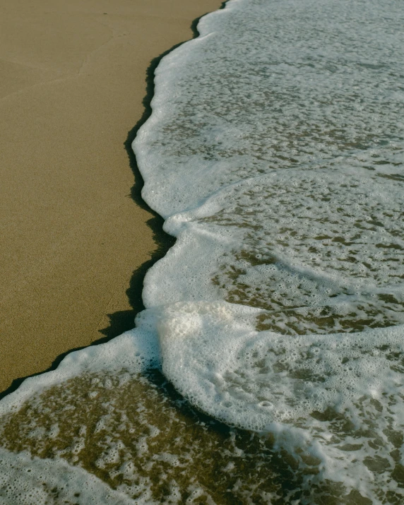 close up s of waves in the sand and the water on the beach