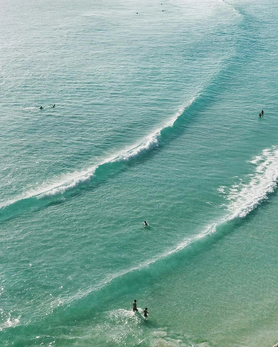 three people in the ocean, one riding a surf board