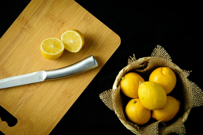 a knife next to a bunch of oranges and a small bowl