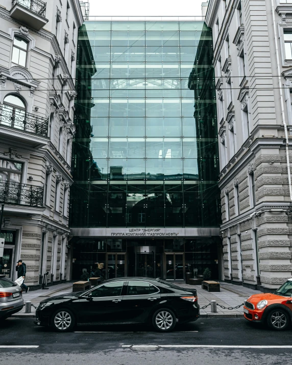 an apartment building with a glass front and a car outside