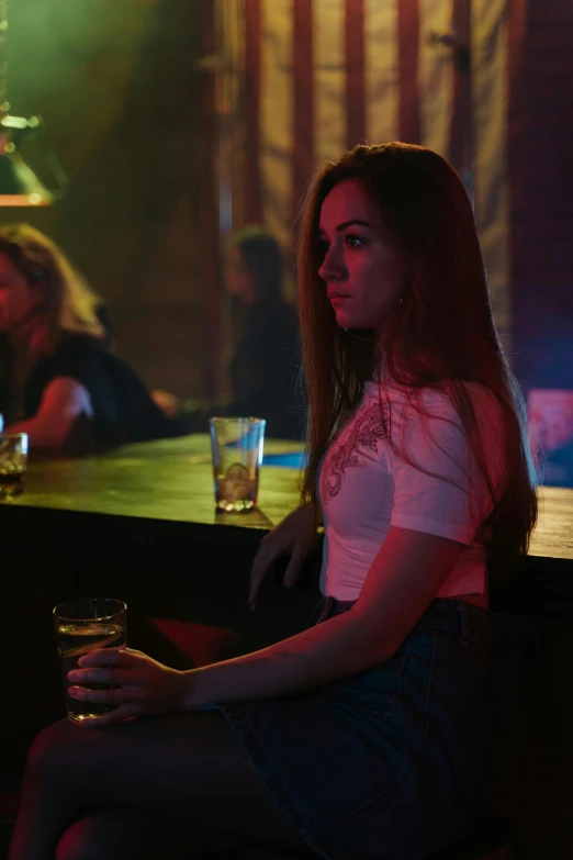 the woman is seated at the bar with a glass