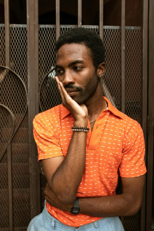 a man is leaning against a fence with his hands together