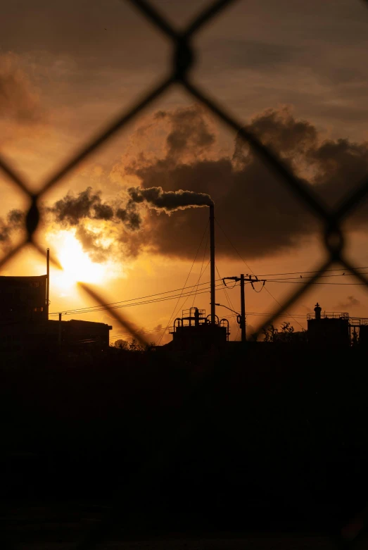 the sun is setting behind some industrial buildings