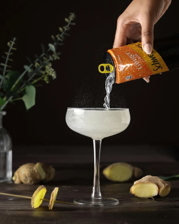 person pouring orange juice into a wineglass filled with a white wine