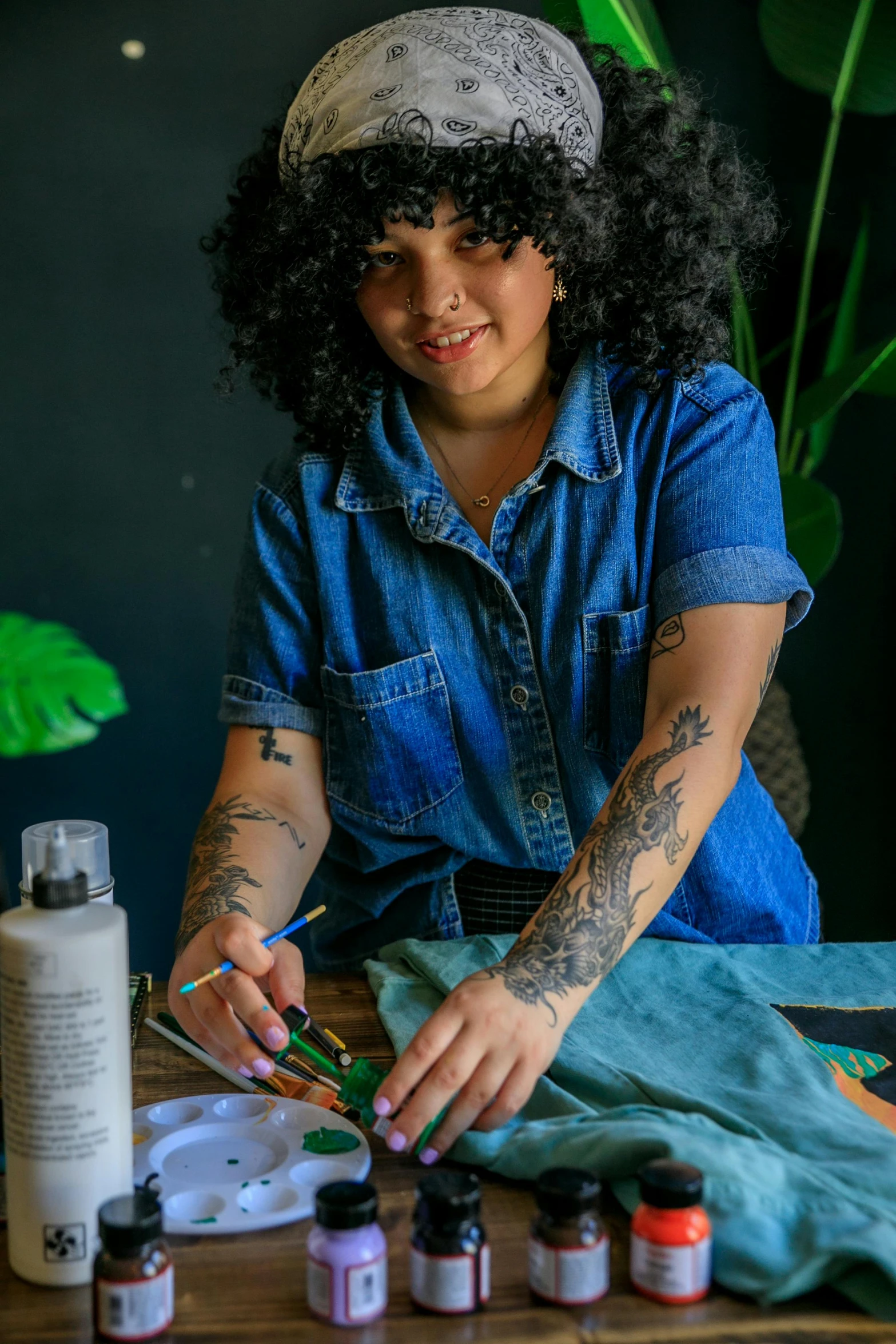 a woman with tattoos and a denim shirt is putting soing on her hands