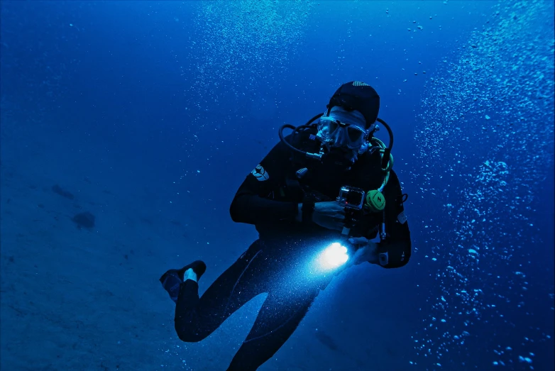 a man dives underwater holding a light