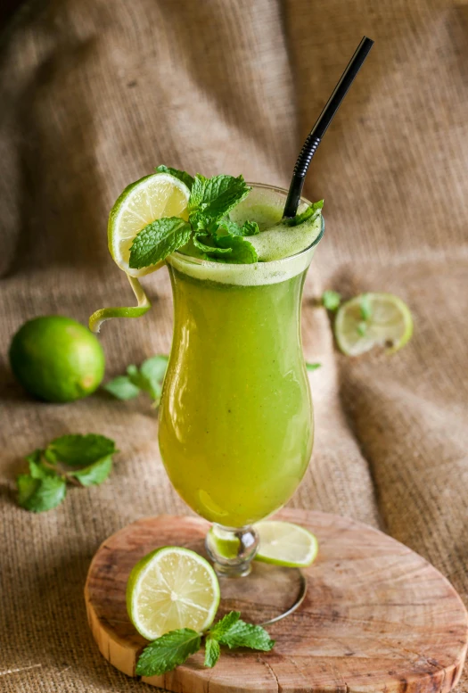 a green cocktail sitting on top of a wooden  board