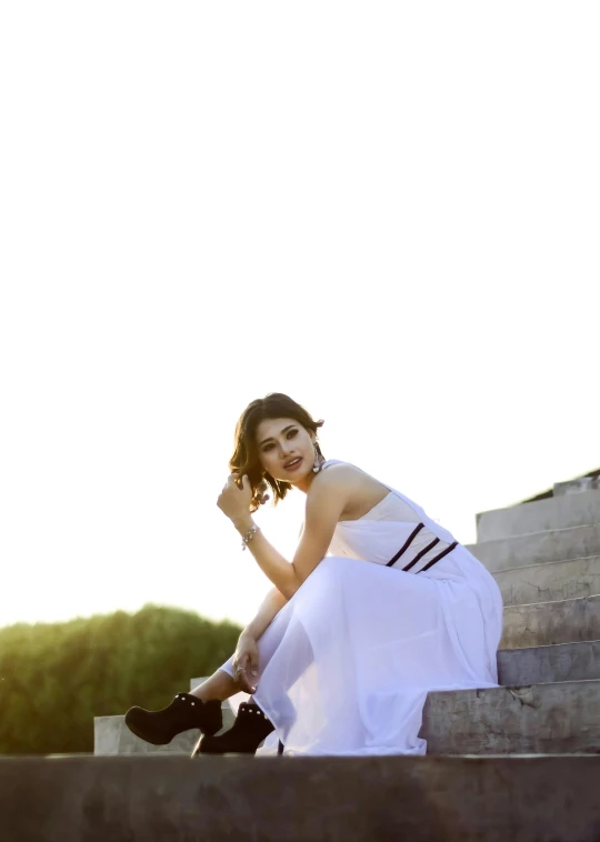 a beautiful woman sitting on stairs in a white dress