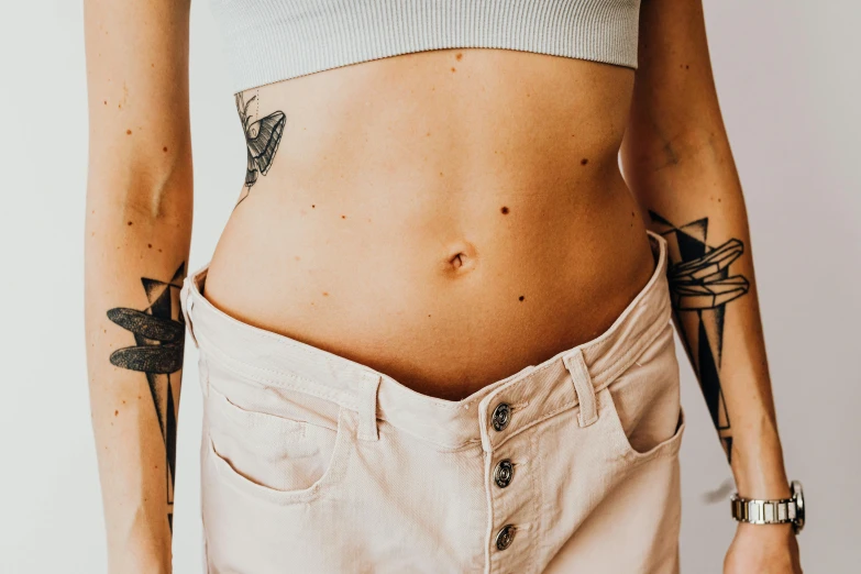 a woman with piercings wearing shorts and holding her stomach exposed