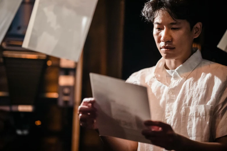 man in white shirt holding papers next to light