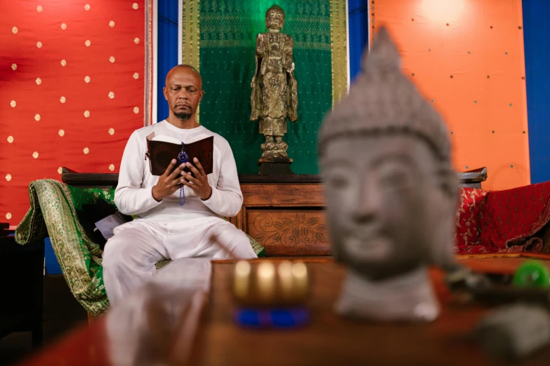 the man is seated with a book in his hands