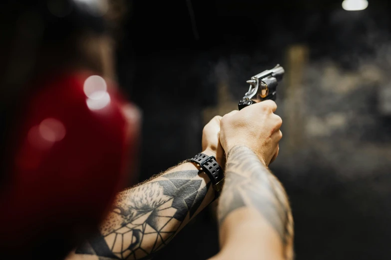 a man wearing tattoos pointing his gun in the air