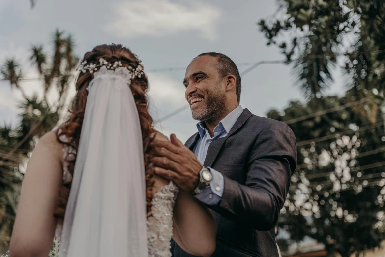 a man standing next to a woman near trees