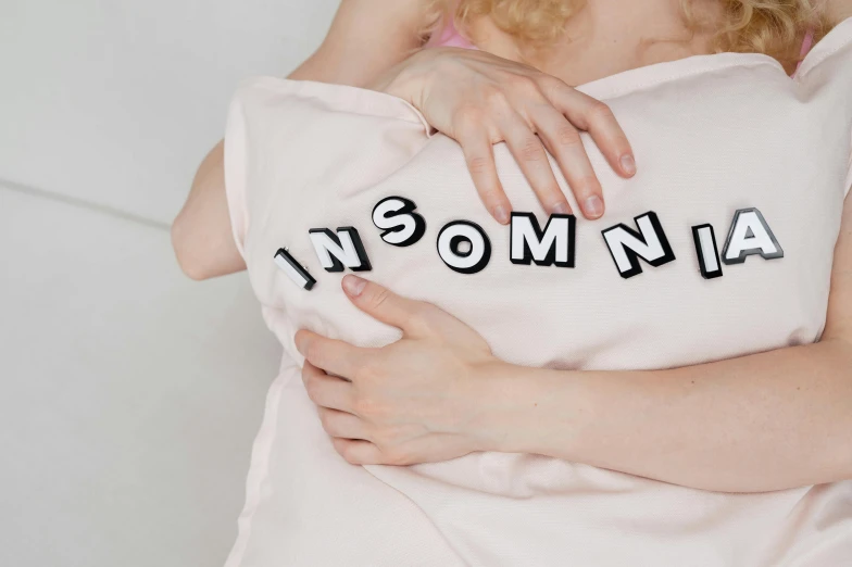 a woman covered in an oversize white towel is pictured hugging the arms of a pillow