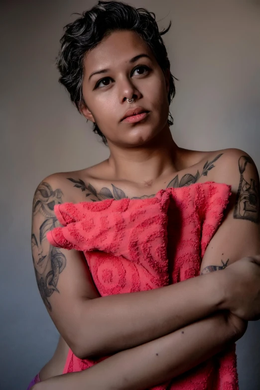 a woman with a tattooed arm is standing and looking off into the distance