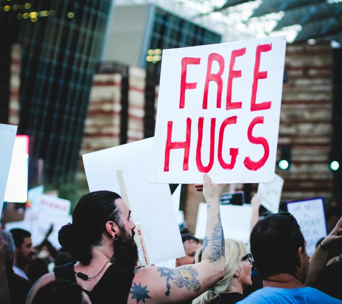 the protestors hold up signs with free hugs on them