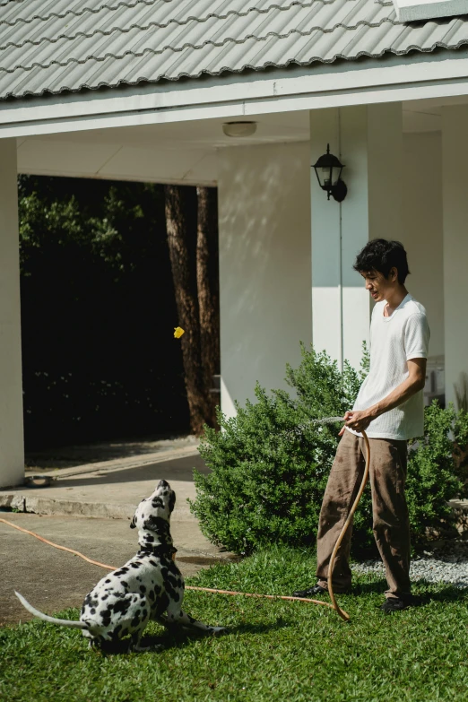 a man with a frisbee walking a black and white dog on a leash