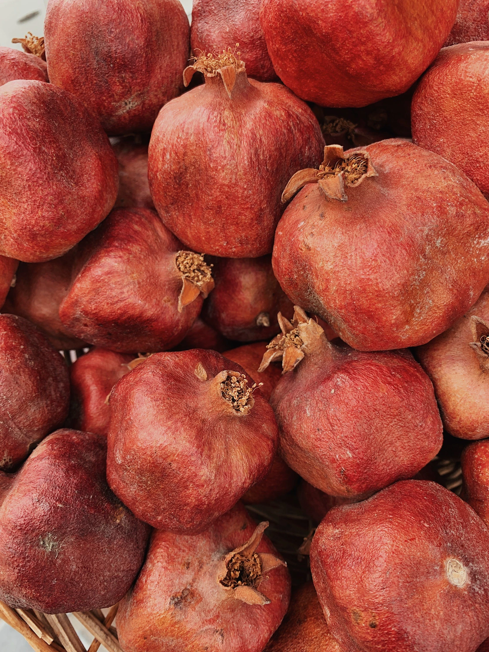 a bunch of red fruit that is stacked up in a basket