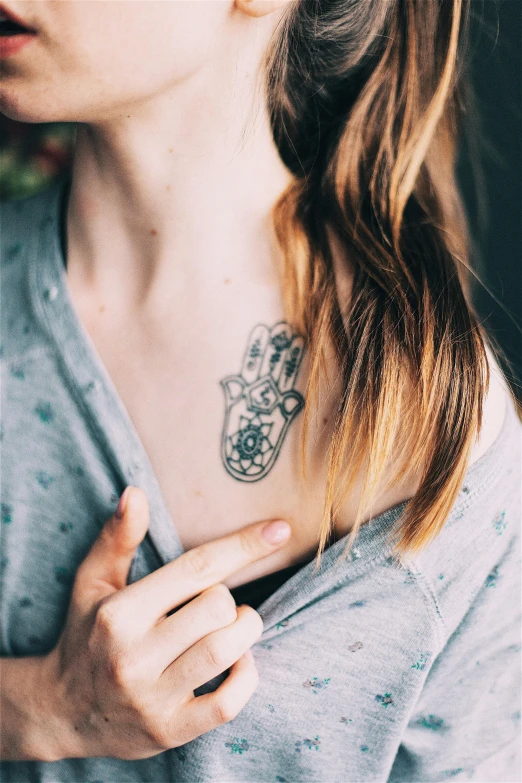 woman with tattoos on her chest looking away