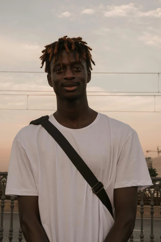 a young man in white shirt and jeans posing with a camera