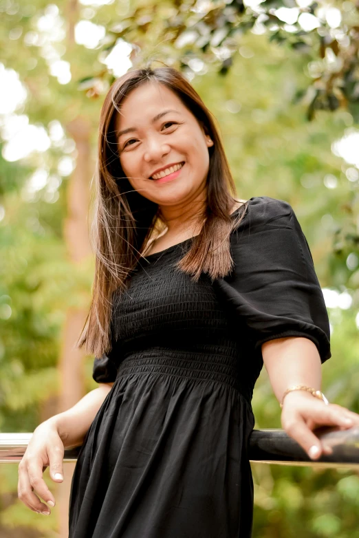 an asian woman is smiling on the edge of a bridge
