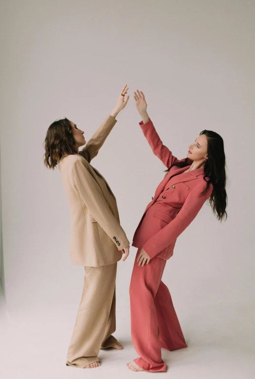 two women in matching clothing high five each other