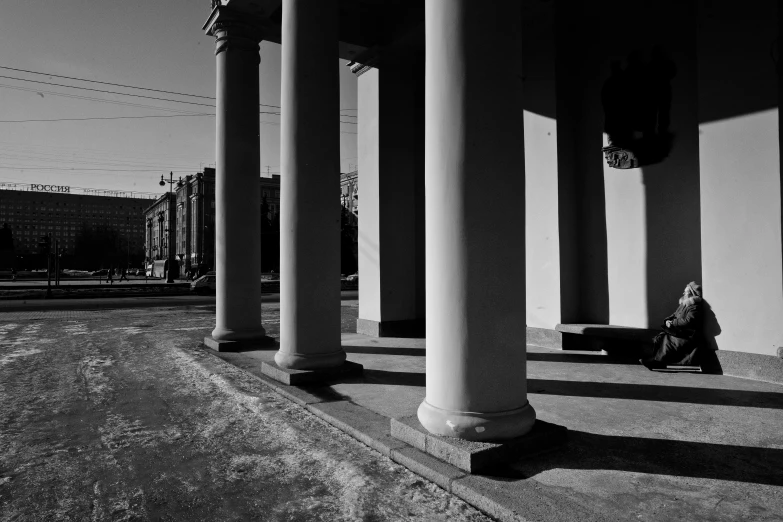 there is a person sitting on the ground under pillars