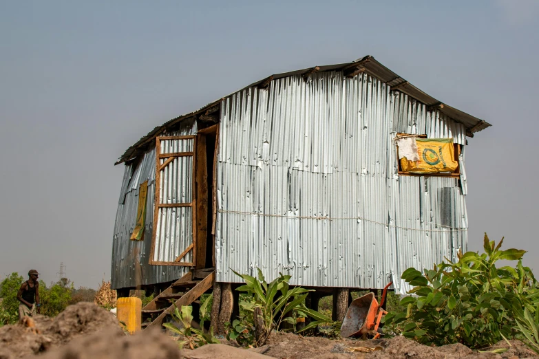 a man sits outside of a shack in a desert area