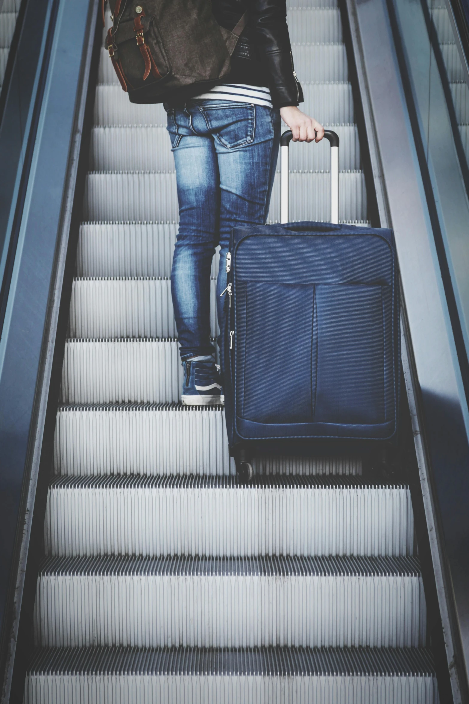 a woman is moving down the escalator with her bag