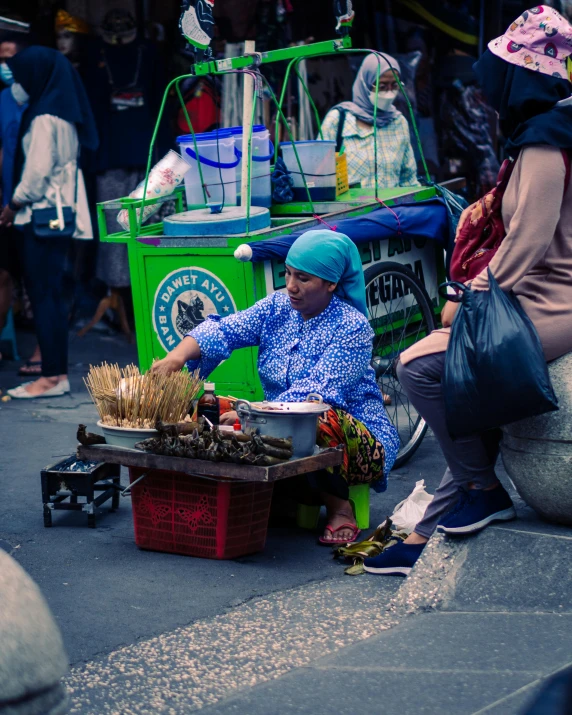 a woman kneeling down to pick up some dried grass