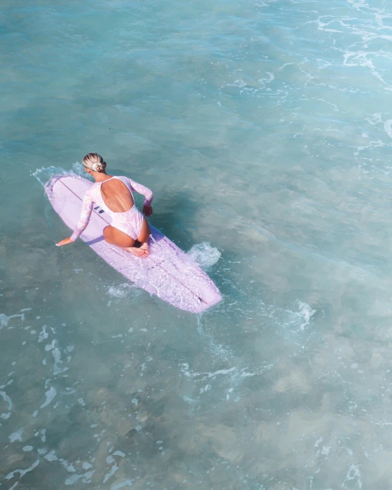 woman in bikini on surf board with blue ocean