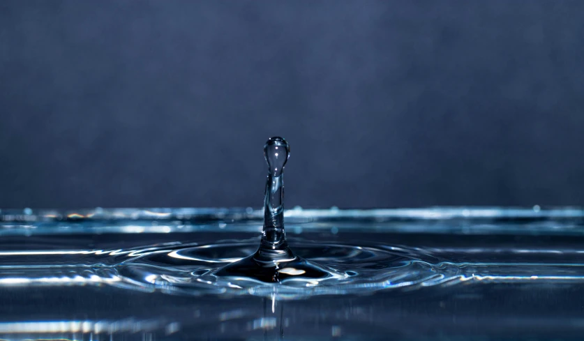 a drop of water splashing onto the ground with a dark background