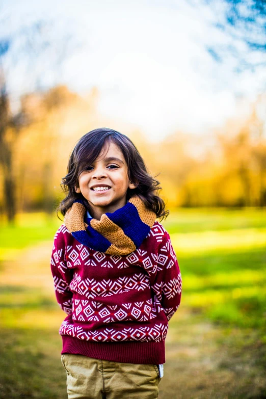 a small child smiling in a park near a tree