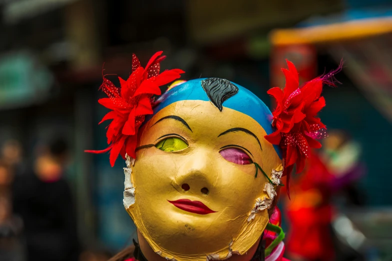 a close up of a yellow mask with red flowers