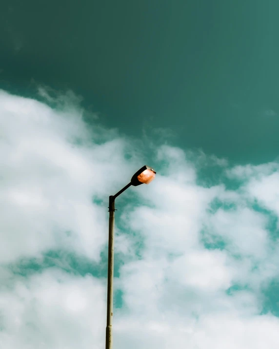 a lamp post is surrounded by clouds in the sky