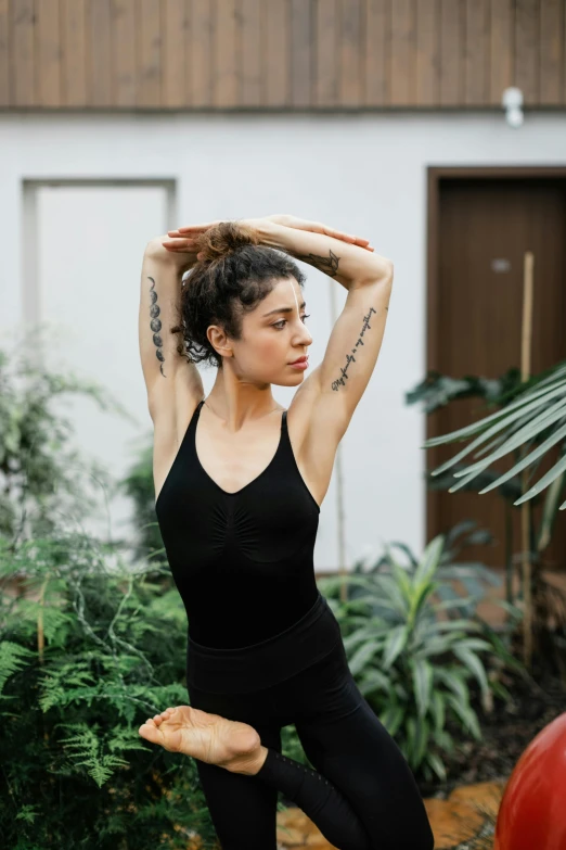 a woman wearing black yoga clothing stretching her arms in a full body workout pose