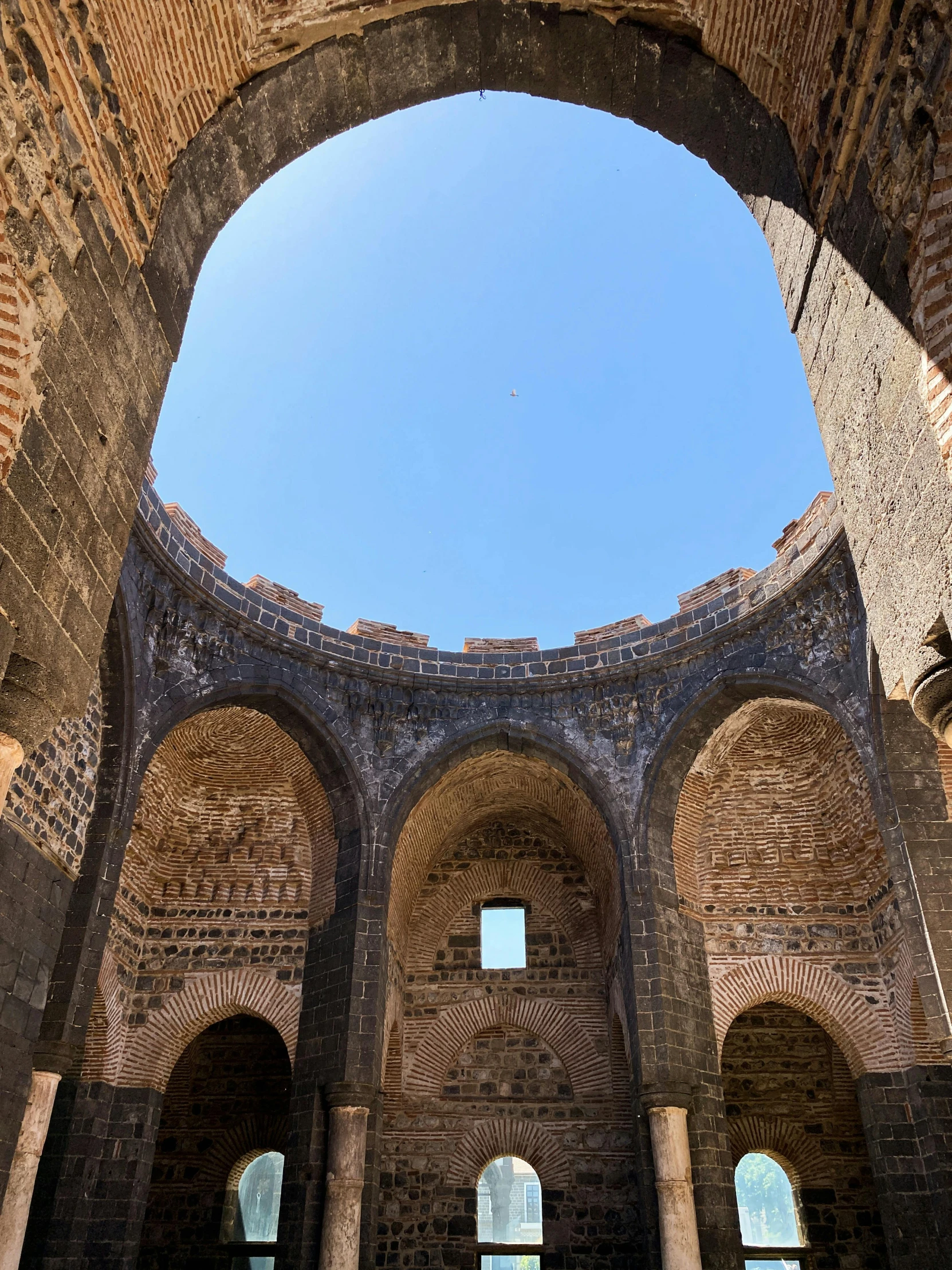 some tall brick pillars and arches are under a clear blue sky