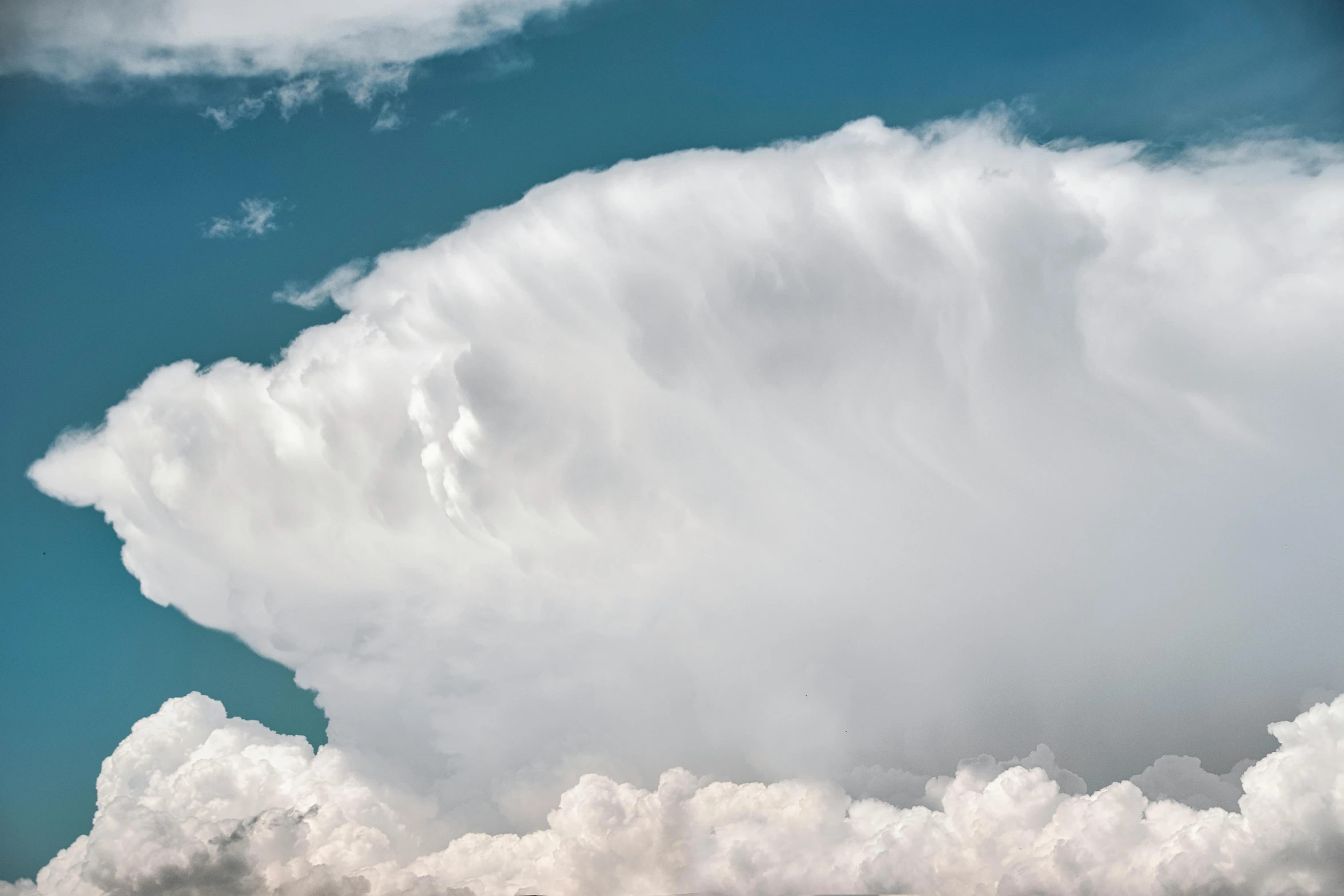 a black jetliner is flying in the sky above a large cloud