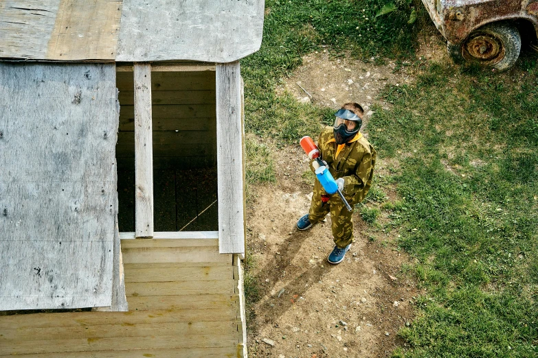 a boy stands in front of a shed on his lawn