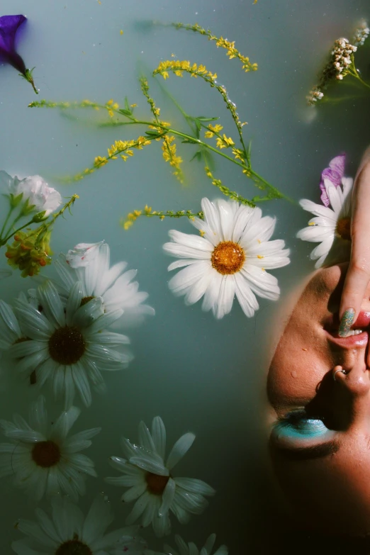 a person's hands next to a water surface and some flowers