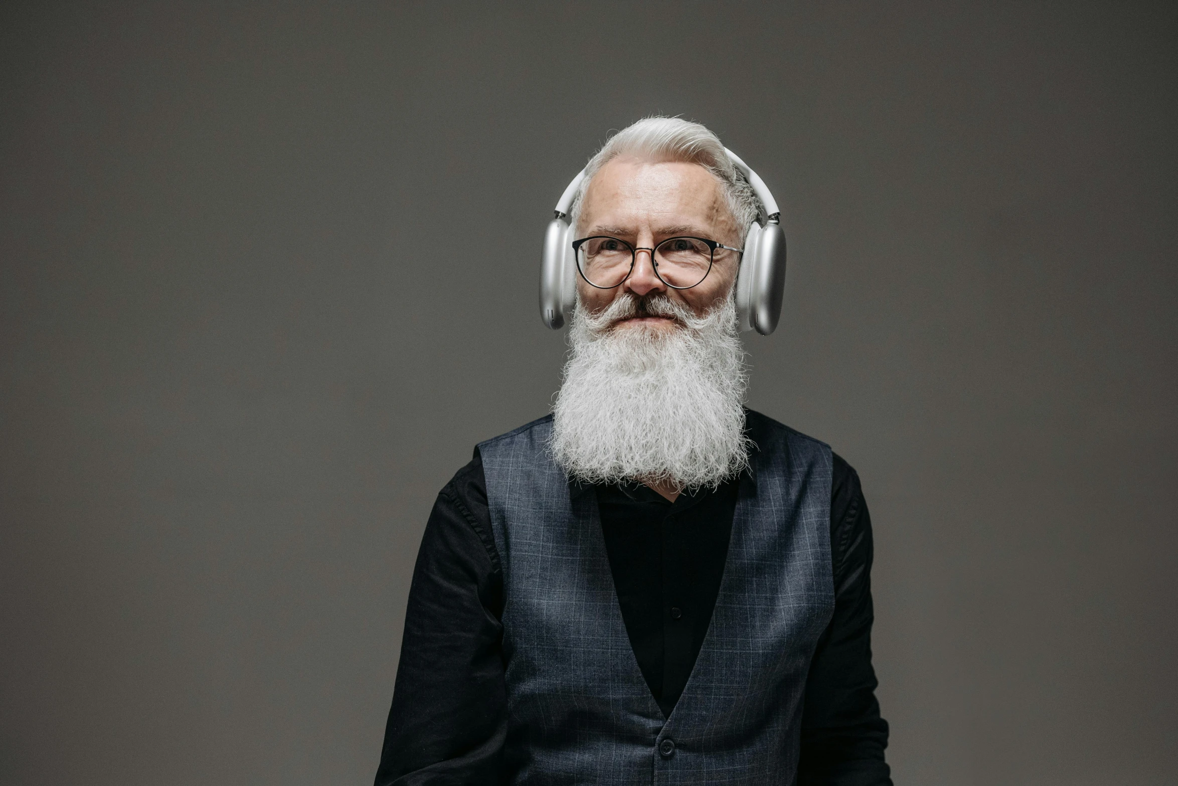 an old man with white hair and glasses wearing headphones