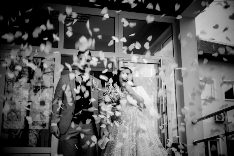 a woman holding a bouquet standing in front of a doorway next to another man